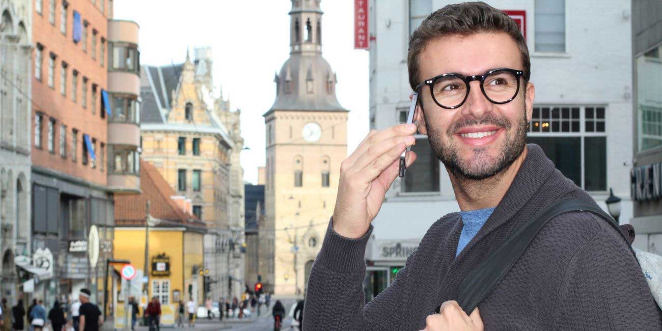 Mann telefoniert mit Handy in fremder Stadt über Geo-Nummer